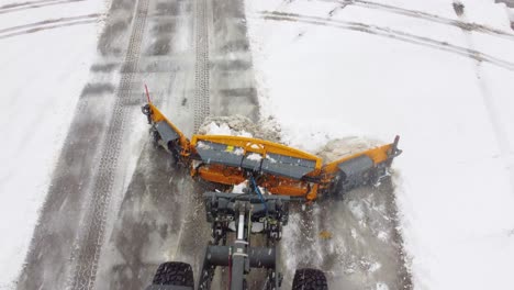 Overhead-view-of-snowplough-clearing-parking-lot-during-snowstorm,-Montreal-Canada