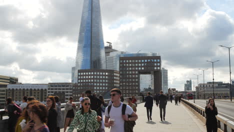 Pendler-Unterschiedlicher-Ethnischer-Herkunft-Auf-Der-London-Bridge,-Im-Hintergrund-Das-Ikonische-Shard-Gebäude,-Unter-Einem-Mit-Wogenden-Wolken-Bemalten-Himmel