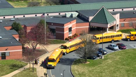 American-School-Buses-in-front-of-school-picking-up-pupils-and-students-from-school-in-USA