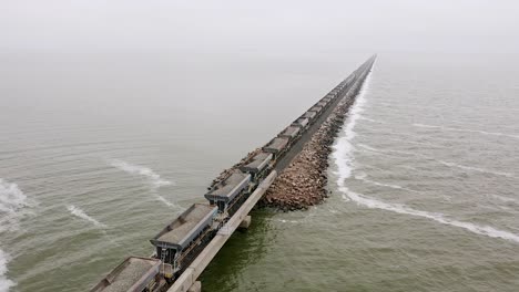 Aerial-of-long-freight-train-carrying-rocks-by-Lake-Picasa,-Argentina