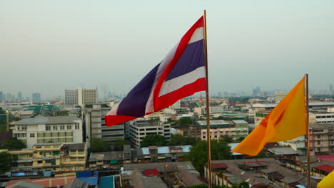 Bandera-Tailandesa-Ondeando-En-Cámara-Lenta-Con-La-Ciudad-De-Bangkok-Al-Fondo