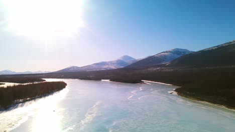 frozen-river-in-Yakutia,-blue-ice,-blue-sky,-gray-forest,-bright-sun