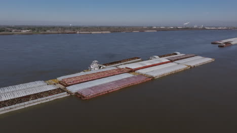 Wide-aerial-footage-focused-on-a-tug-boat-that-is-pushing-against-a-barge-full-of-scrap-metal-in-Baton-Rouge,-Louisiana