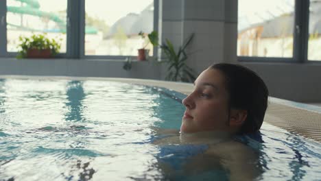 A-young-woman-is-seen-in-a-pool,-relaxing-after-a-swim