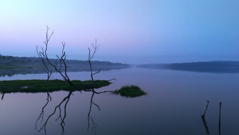 Morning-calm-lake-,-before-sun-lake-reflecting-the-atmospheric-effects-of-the-sky-and-surrounded-by-misty-fogs