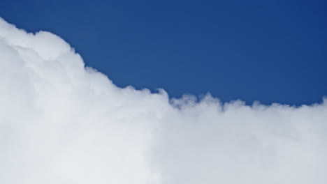 Pure-white-cloud-slowly-changes-shape-in-blue-sky,-abstract-tele-view