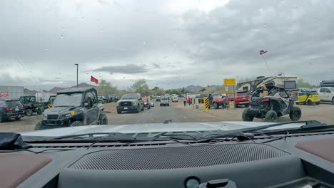 POV---Driving-around-pedestrians-and-vehicles-to-find-parking-near-the-big-tent-for-Sports,-Vacation-and-RV-Show-with-a-million-attendees,-on-rainy-day