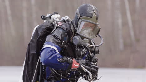 Water-drips-from-ice-diver-in-drysuit-emerging-from-freezing-ice-lake,-scuba