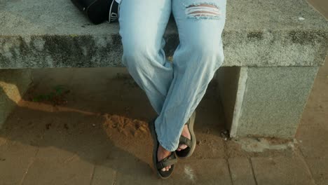 Young-woman-is-sitting-on-a-bench-with-their-legs-crossed