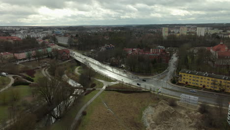 Aerial-view-of-a-bridge-over-a-park-in-Olsztyn,-with-surrounding-streets-and-buildings