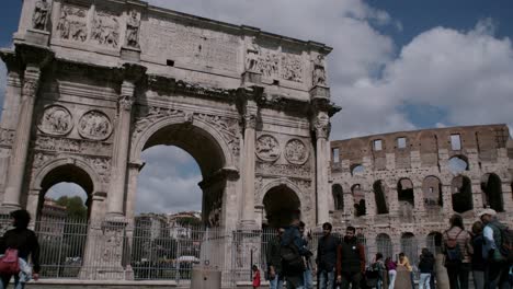 Turistas-Y-Peregrinos-Cerca-Del-Arco-De-Constantino,-El-Coliseo-Romano-En-Segundo-Plano.