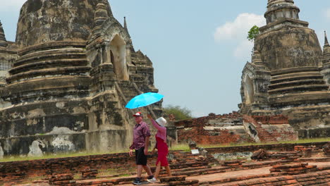 Woman-protecting-husband-from-sun-in-hot-day,-Ayutthaya