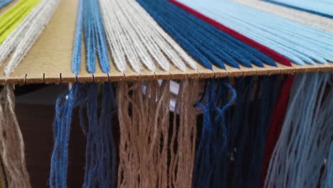Strands-of-a-yarn-threads-hanging-over-the-weaving-board
