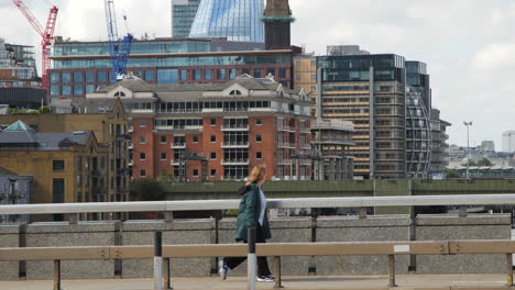 In-slow-motion,-a-cyclist,-London-bus,-and-pedestrians-move-to-the-right-of-the-camera,-set-against-the-backdrop-of-London's-iconic-buildings