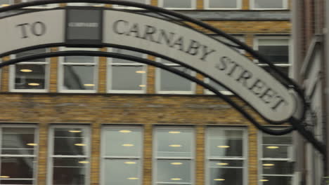 Pan-across-Welcome-to-Carnaby-Street-sign-over-Carnaby-Street-London,-Day