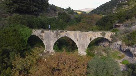 Ancient-Stone-Aqueduct-in-Crete:-Aerial-View-of-a-Historic-Structure-Spanning-a-Verdant-Valley