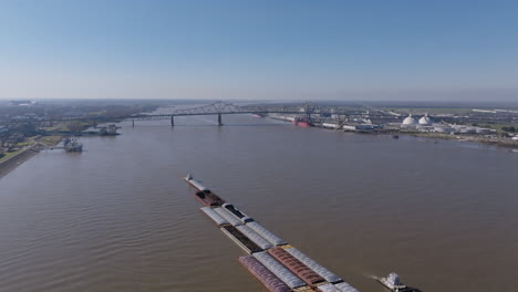 Wide-aerial-footage-of-a-couple-of-tugboats-pushing-a-large-amount-of-barges-on-the-Mississippi-River-in-Baton-Rouge,-Louisiana