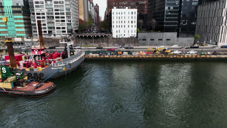 Aerial-tracking-shot-in-front-of-a-construction-vessel-in-front-of-the-FDR-drive-in-NYC