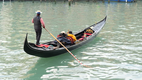 Tracking-shot-of-elderly-couple-taking-a-gondola-ride-in-Venice,-Italy