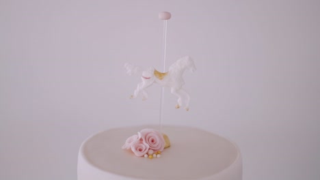 Elegant-cake-topped-with-a-whimsical-flying-horse-and-delicate-pink-roses