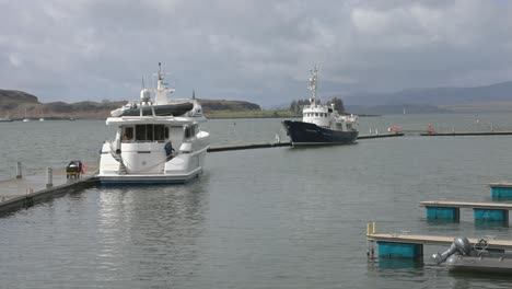 Hand-held-shot-of-workers-walking-around-the-yachts-docked-at-Oban-Harbour