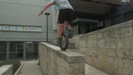 Energetic-and-confident-man-balancing-and-jumping-on-a-unicycle-in-city-neighbourhood