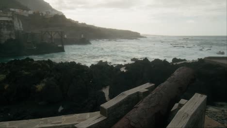 Waves-crashing-on-the-rocky-coast-of-Garachico,-old-rusty-cannon-on-Tenerife,-Canary-Islands