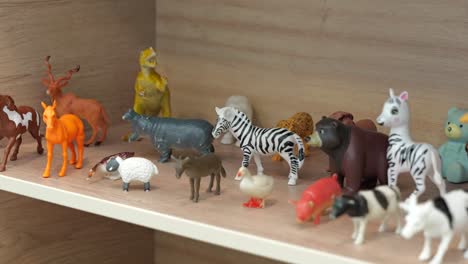 Small-plastic-toy-animals-on-shelf-in-kindergarten-classroom,-close-up-tracking