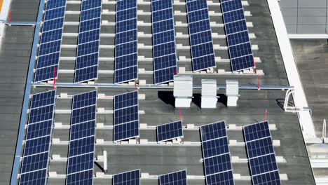 Photovoltaic-modules-on-a-building-roof,-on-a-summer-day---Telezoom-drone-shot