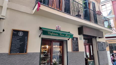 Palma-De-Mallorca-urban-street-with-motorcyclist,-pedestrian-and-a-cafe-in-a-lovely-building-with-a-balcony-in-the-centre-of-the-city