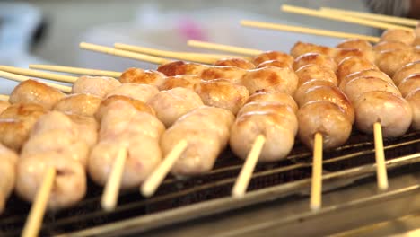 Sausages-skewered,-grilling-over-flames,-creating-savory-aromas,-as-heat-chars-and-caramelizes,-promising-delicious-bites-of-smoky-delight