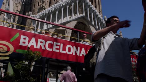 Tourists-on-Barcelona-city-tour-bus-admiring-the-Sagrada-Familia-on-a-sunny-day,-low-angle-view