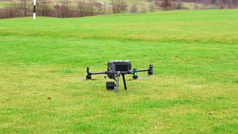 Drone-Industrial-Pesado-Aterrizando-En-Un-Campo-De-Hierba-Verde-Con-Carga-útil-De-Cámara-Avanzada