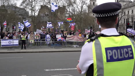 Un-Oficial-De-La-Policía-Metropolitana-Observa-A-La-Gente-Con-Banderas-Y-Pancartas-En-Una-Protesta-Pro-israelí-En-La-Plaza-Del-Parlamento-Durante-El-Día-De-Al-Quds.