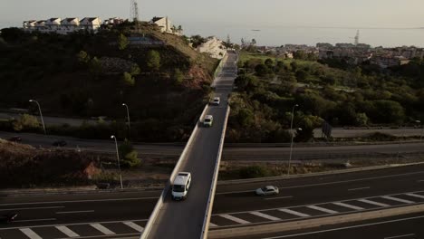 Luftaufnahme-Von-Hinten-Eines-Wohnmobilkonvois,-Der-Eine-Autobahnbrücke-In-Der-Nähe-Von-Malaga,-Spanien-überquert