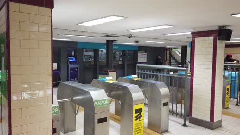 Vintage-Underground-station-turnstiles-lady-goes-out-with-umbrella-rainy-urban-scene-of-public-metro-service-entrance-of-buenos-aires-city,-argentina