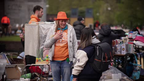 Older-Dutch-woman-with-blonde-hair-and-orange-head-talks-friendly-during-King's-day