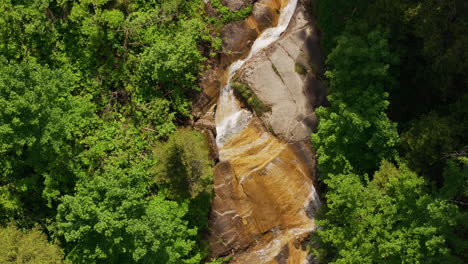 Aerial-of-a-small-mountain-creek-surrounded-by-a-green-forest