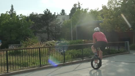 An-energetic-adult-man-balancing-and-jumping-on-a-unicycle-in-urban-garden-space