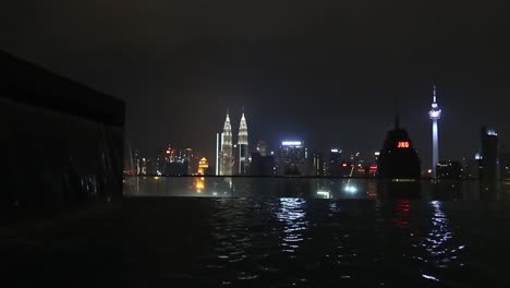 Horizonte-De-Rascacielos-De-La-Ciudad-Por-La-Noche-Visto-Desde-La-Piscina-Infinita-De-La-Azotea,-Kuala-Lumpur