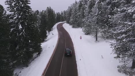 Aerial-tracking-shot-of-Peugeot-car-on-Lavaze-Pass-Road-during-snowy-winter-in-Italian-mountains