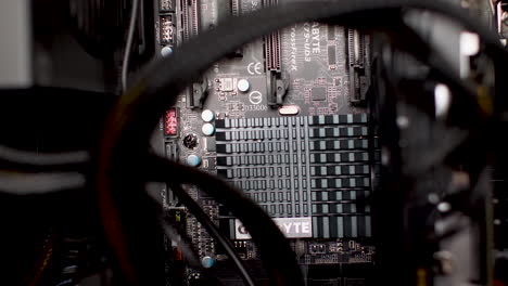 Close-up-shot-of-the-computer-motherboard,-with-the-main-cooler-efficiently-dissipating-heat-from-microchips-below,-surrounded-by-PCI-slots-and-cables,-representing-the-concept-of-efficient-hardware