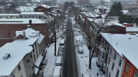 Slow-aerial-flight-over-narrow-snowy-street-in-american-town-in-Winter