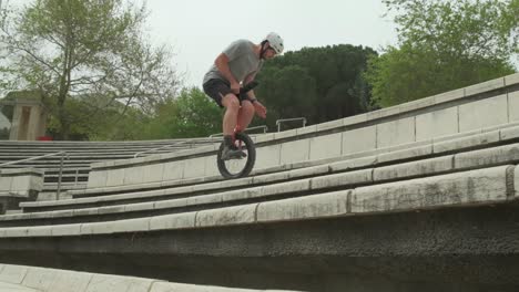 A-confident-and-energetic-male-unicyclist-jumping-upward-at-stairs