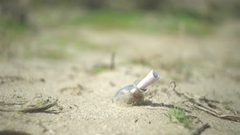 A-girl-walking-past-a-bottle-on-the-ground-in-the-sandy-desert-with-a-note-inside-it-as-the-camera-racks-focus
