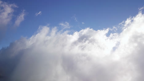 Billowing-white-clouds-grow-wispy-tendrils-reaching-up-into-blue-sky