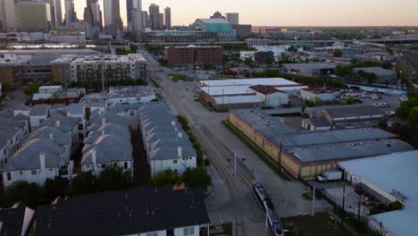 Aerial-view-following-the-Metro-approaching-the-downtown-of-Houston,-sunrise-in-USA