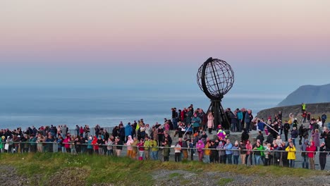 Drohnenaufnahme-Von-Touristen-Rund-Um-Das-Globus-Denkmal-Am-Nordkap-Von-Norwegen-Nach-Sonnenuntergang,-60 fps