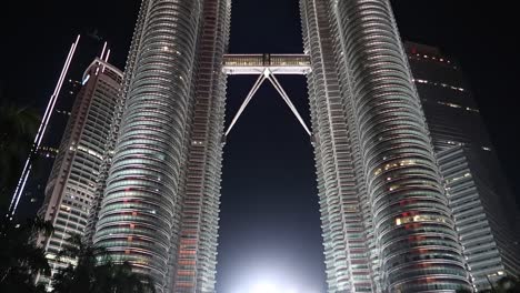 Petronas-Twin-Towers-of-Kuala-Lumpur-at-Night,-tilt-down-from-top-to-Crowd-at-Base