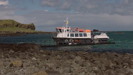 Toma-De-Seguimiento-De-Un-Barco-De-Staffa-Tours-Que-Coloca-La-Pasarela-En-La-Orilla-De-Lunga.